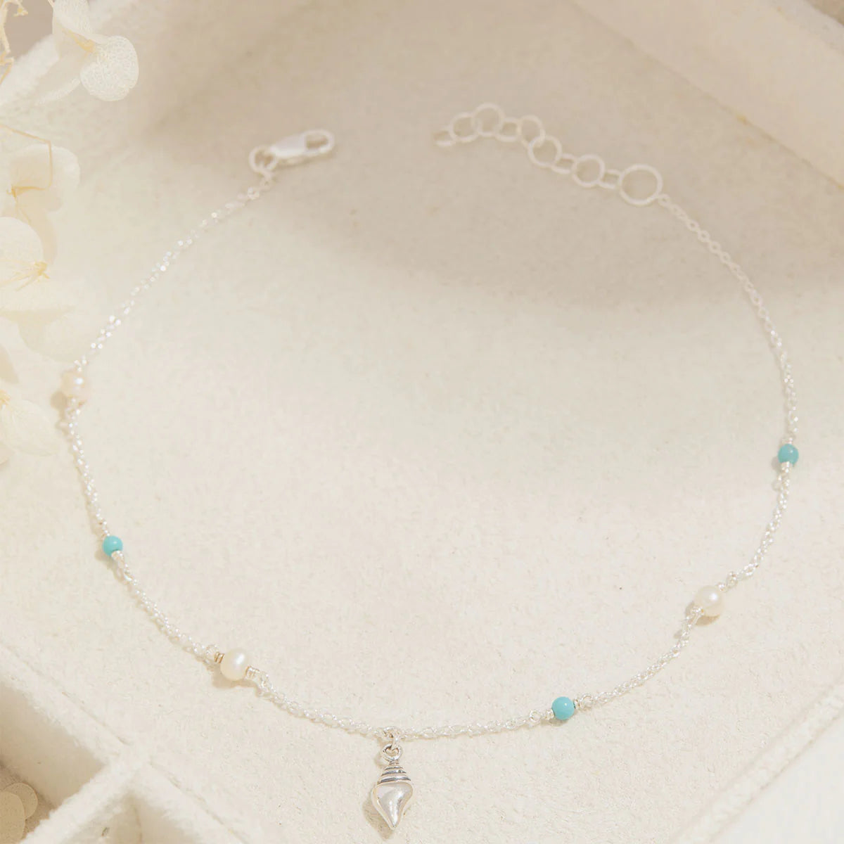 Delicate anklet with small beads on a white background