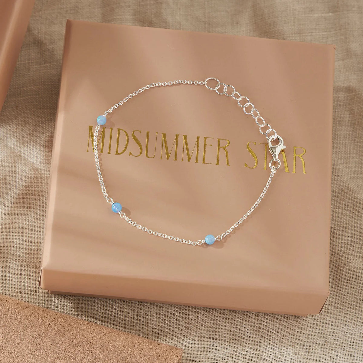 Silver bracelet with opal beads on a 'Midsummer Star' branded box.