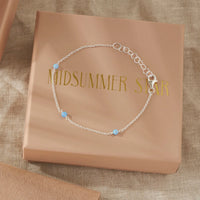 Silver bracelet with opal beads on a 'Midsummer Star' branded box.
