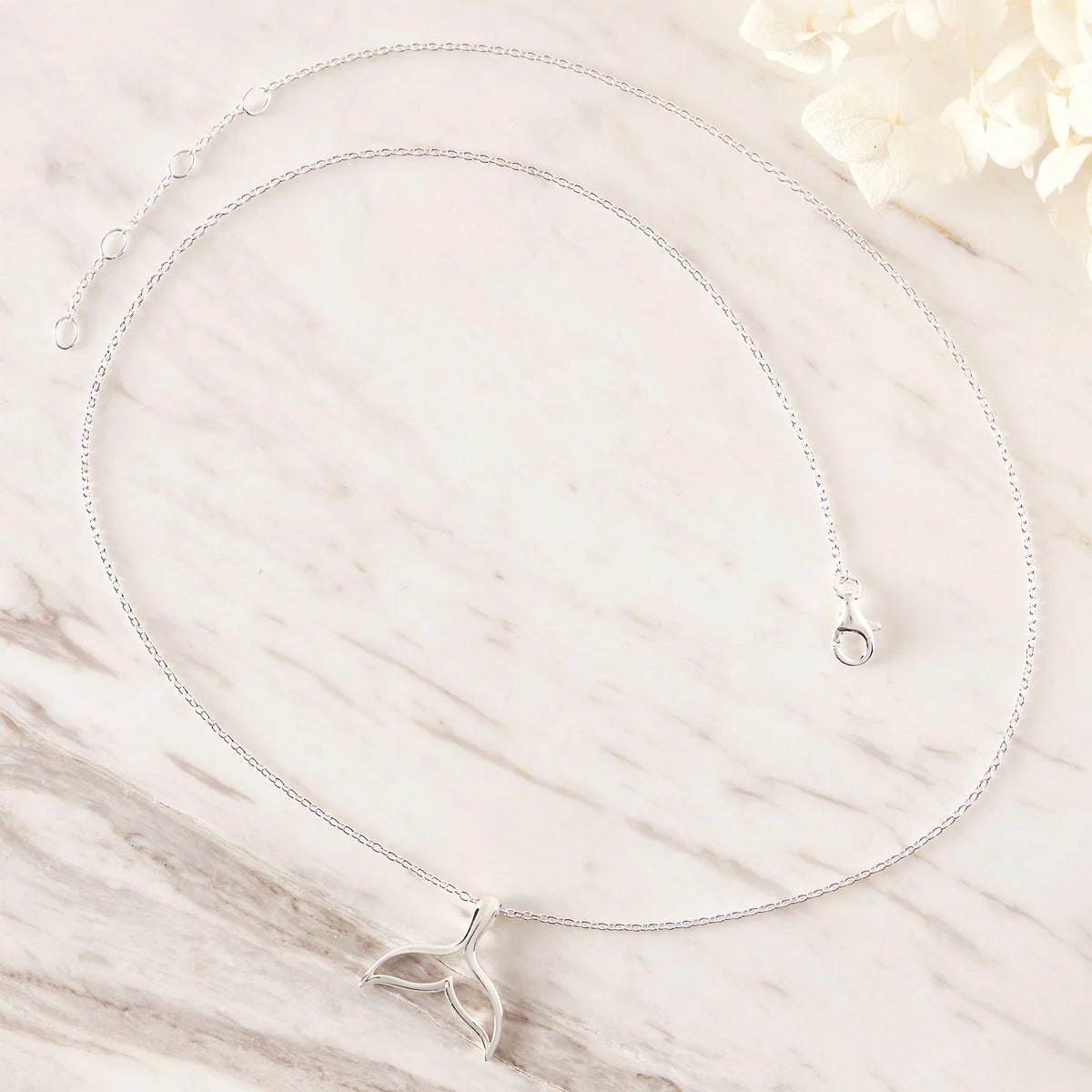 Silver necklace with a delicate pendant on a marble surface