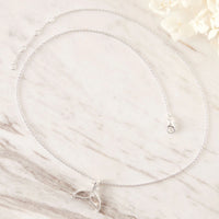 Silver necklace with a delicate pendant on a marble surface