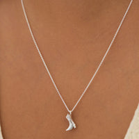 Silver boot-shaped pendant necklace on a person's neck