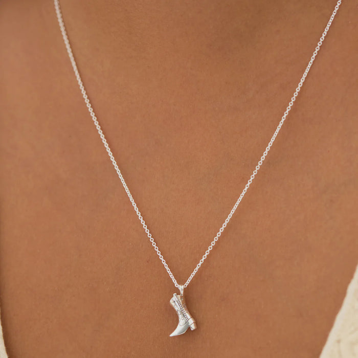 Silver boot-shaped pendant necklace on a person's neck
