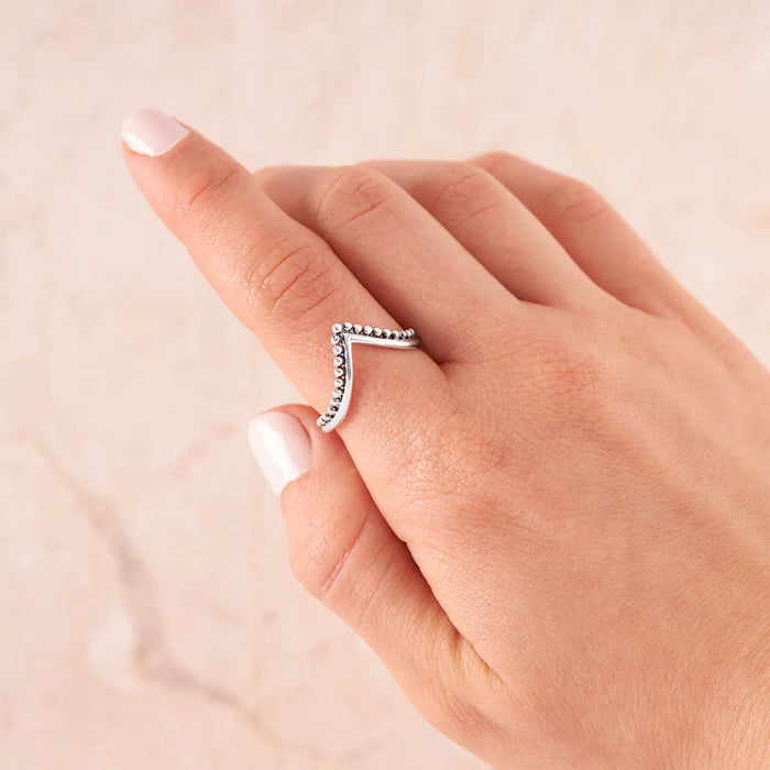 Silver ring on a finger against a beige background