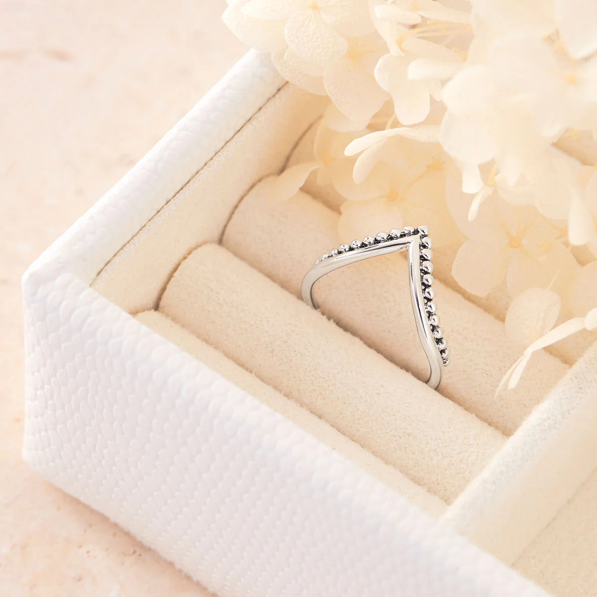 Silver ring with bead design in a white jewelry box