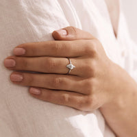 Hand wearing a silver ring with a seashell design on a light background