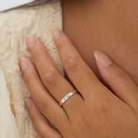 Hand wearing a silver ring on a textured fabric background