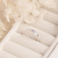 Silver ring in a jewelry box with white flowers in the background
