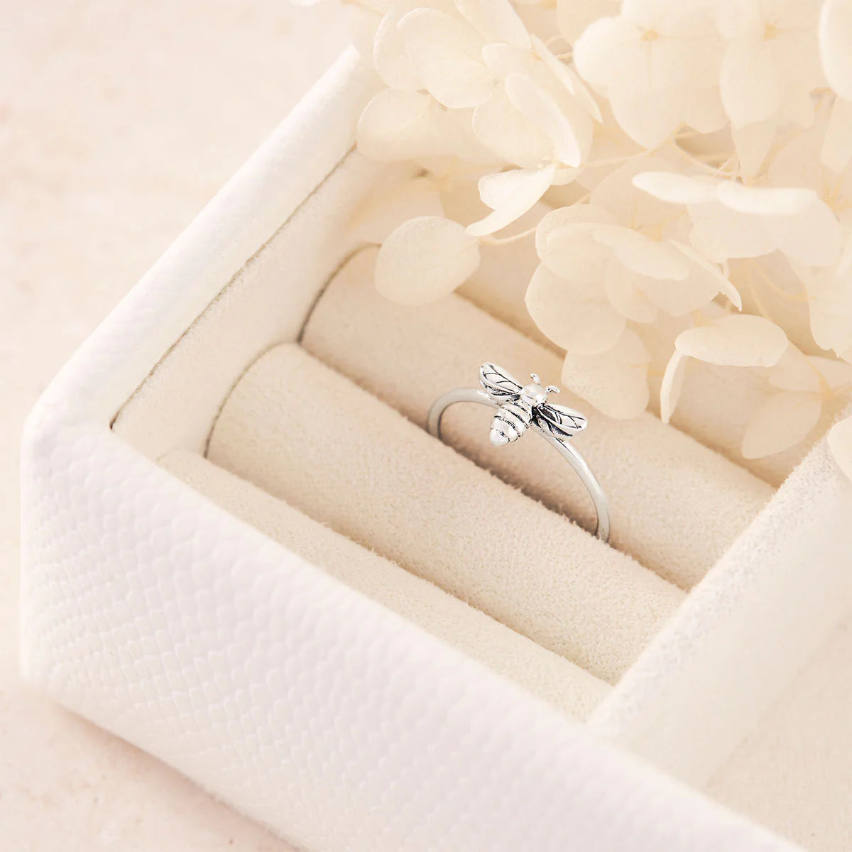 Silver ring with bee design in a white jewelry box