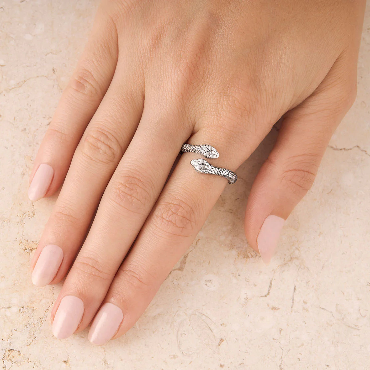 Silver ring on a finger with a light beige background