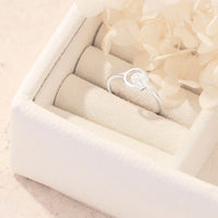 Silver ring with a circular cresent moon cutout design in a white jewelry box