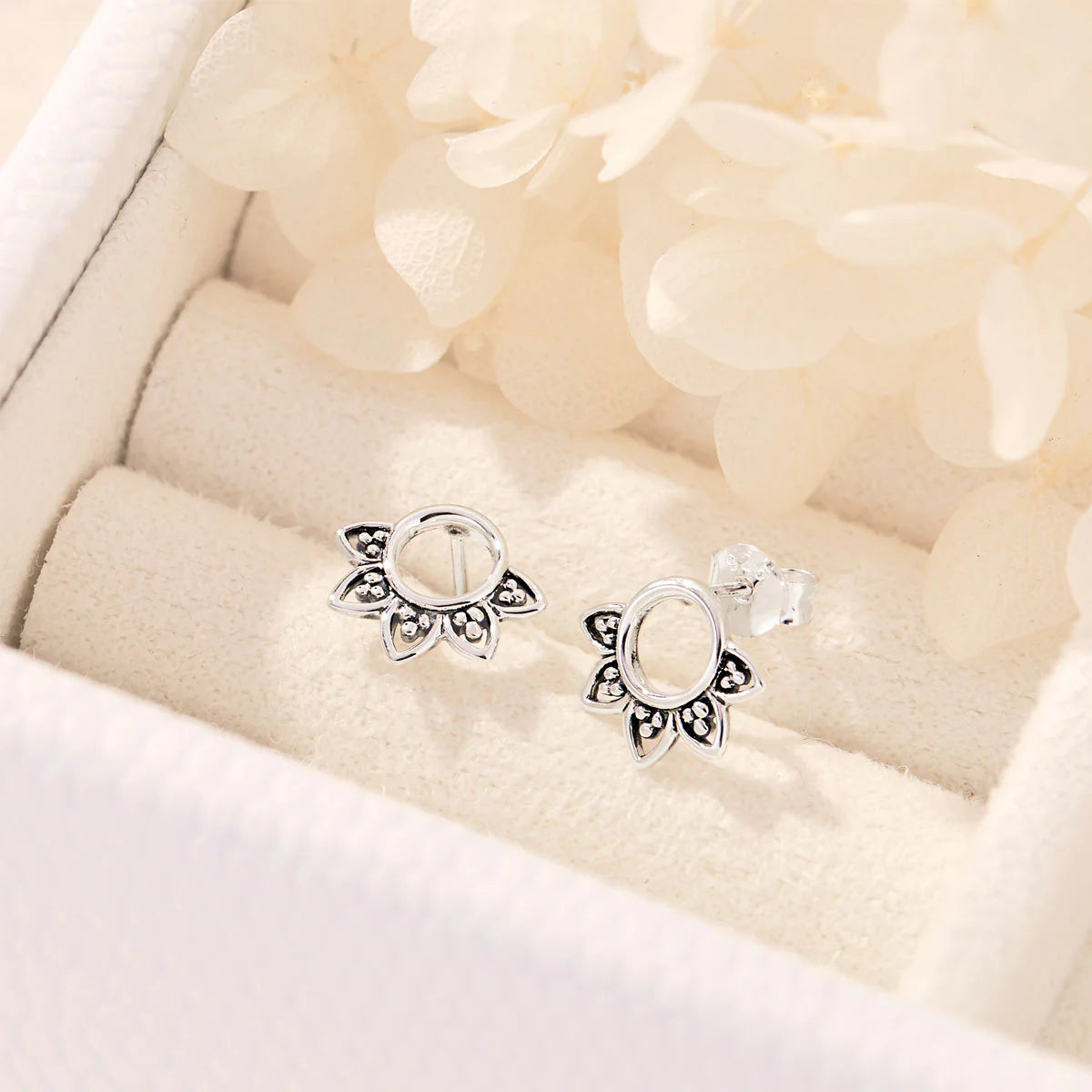 Pair of silver earrings on a soft beige fabric background