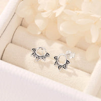 Pair of silver earrings on a soft beige fabric background