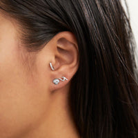 Close-up of an ear wearing two silver earrings with dark hair.