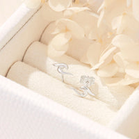 Silver wave-shaped studs on a soft beige fabric background.